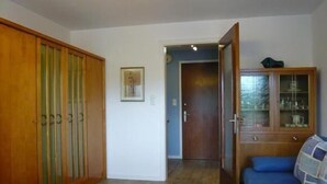 Una stanza con un'armadio in legno, un divano blu, un mobile con vetrine e un quadro appeso al muro.