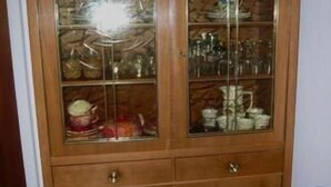 Un mobile in legno con ante in vetro che contiene stoviglie da cucina.