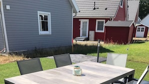 Un tavolo rettangolare all'aperto con sei sedie, su un patio lastricato con una casa sullo sfondo.