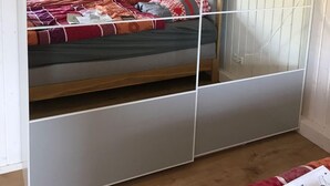 Una stanza con un letto, pareti bianche e un soffitto in legno.