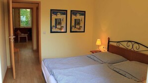 A bedroom with a bed, a nightstand with a lamp, and two framed pictures on the wall. - Strandnahe Ferienwohnung im Ostseebad Göhren (Göhren)