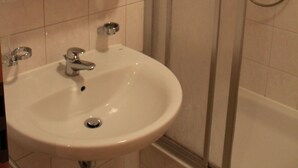 A bathroom with a white sink, a mirror, and a glass-enclosed shower. - Strandnahe Ferienwohnung im Ostseebad Göhren (Göhren)