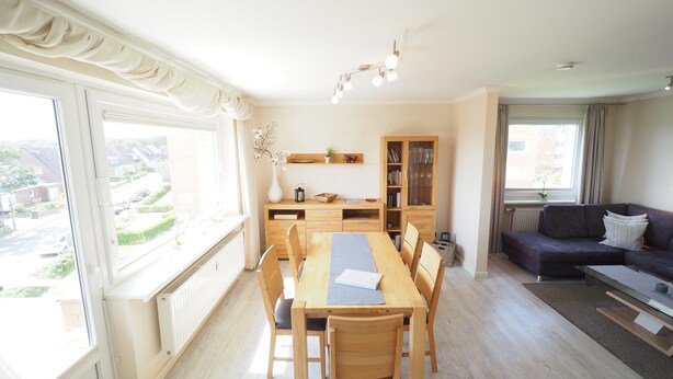 Amplia sala de estar con una mesa de comedor, sillas, un sofá y una estantería.