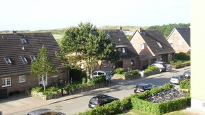 Una calle residencial con casas, coches aparcados y bicicletas.