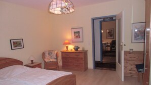A bedroom with a wooden bed, a chair, a dresser, and a lamp. - Haus Halligblick, Ferienwohnung Pellworm (Dagebuell)