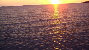 A sunset over a calm sea with a distant shoreline. - Haus Halligblick, Ferienwohnung Pellworm (Dagebuell)