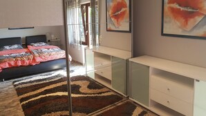 Un dormitori modern amb un llit gran, una separació de vidre i obres d'art a les parets.