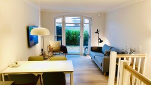 A modern living room with a dining area, a staircase, and a view of the outdoors. - Ankerplatz-sylt Haus Mateika - Wohnen Sie Exklusiv im Herzen von Westerland (Sylt)