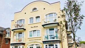 A multi-story building with a yellow facade, multiple balconies, and a sign indicating it is a hotel. - Ankerplatz-sylt Haus Mateika - Wohnen Sie Exklusiv im Herzen von Westerland (Sylt)