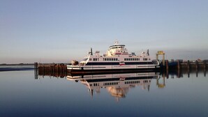 Un ferry atracado en un muelle, con una superficie acuática tranquila que refleja su estructura.