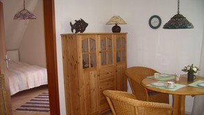 Un comedor con sillas de mimbre, un armario de madera y una mesa dispuesta para dos.