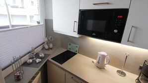 A compact kitchen with a microwave, kettle, and coffee maker. - Nordmarkhof (Sylt)