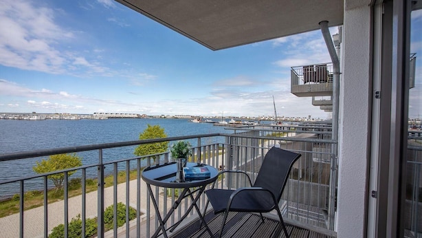 A balcony with a table and chairs overlooking a waterfront. - 2-zi-hafenwohnung Reeder's Nest Olpenitz (Kappeln)