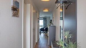 A modern hallway with a wooden floor, a dining area with a table and chairs, and a view of the outdoors. - 2-zi-hafenwohnung Reeder's Nest Olpenitz (Kappeln)