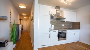 A modern kitchen with white cabinets, stainless steel appliances, and a wooden floor. - 2-zi-hafenwohnung Reeder's Nest Olpenitz (Kappeln)
