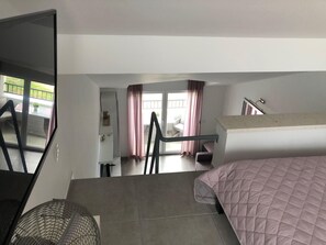 A bedroom with a bunk bed, a fan, a sliding door to a balcony, and a view of the outside. - Studioapartment "carpe Diem" (Kastela)