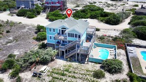A beachfront property with a large house, a swimming pool, and a beach view.