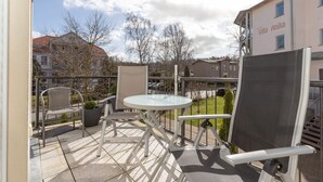 A balcony with a round table, two chairs, and a potted plant. - Villa Katharina, WE 5 / 9965 (Kuehlungsborn)