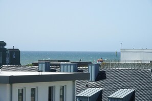Una azotea con vista al mar, que muestra varios edificios y un faro a lo lejos.