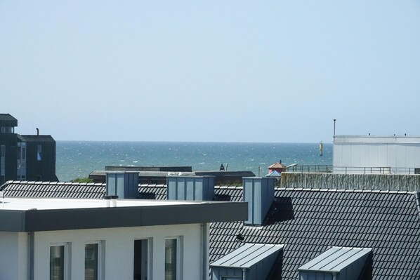 Una azotea con vista al mar, que muestra varios edificios y un faro a lo lejos.