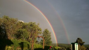 A garden with a wooden pergola and a rainbow. - Ferienwohnung Däumler (Breitenbrunn/Erzgeb.)