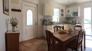 Una cocina con una mesa de madera, sillas, un tazón de fruta y un refrigerador.