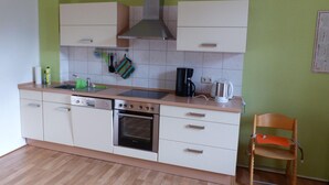 A compact kitchen with white cabinets, a built-in oven, a stove, and a coffee maker. - Vis-a-vis Berliner Tor (Schwerin)