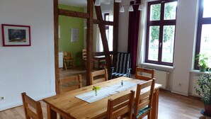 A dining area with a wooden table and chairs, a potted plant, and a view of the outdoors through large windows. - Vis-a-vis Berliner Tor (Schwerin)