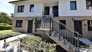 Un bâtiment moderne à deux étages, doté d’un escalier central, d’un petit jardin et d’un chemin piétonnier dallé.