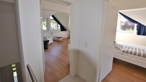 Une chambre avec un lit, un petit coin salon et une fenêtre avec des rideaux.