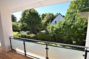 A balcony with a view of a house surrounded by trees.