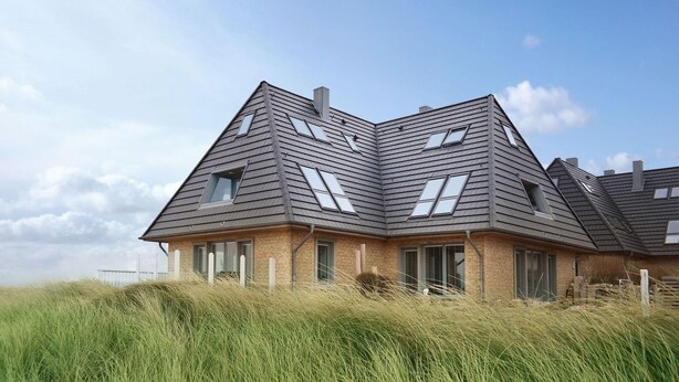 A modern house with a sloped roof, multiple skylights, and a brick exterior.