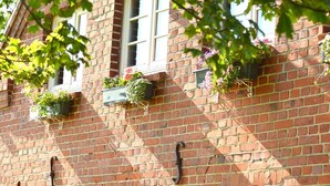 Un bâtiment en briques doté de nombreuses fenêtres, dont certaines sont ornées de jardinières.