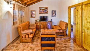 A cozy living room with wooden furniture, a television, and artwork on the walls.