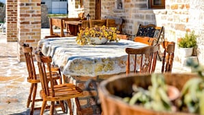 An outdoor dining area with a stone wall, wooden furniture, and a table covered with a white cloth.