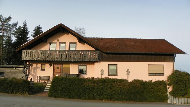A two-story house with a balcony, a front door, and a small porch area. - am Weissenstädter See (Weissenstadt)