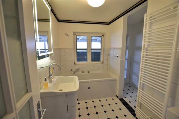 Un baño con lavamanos blanco, bañera y ventana.