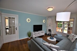 A living room with a sofa, TV, and a fireplace. - Haus am Strandweg H $$$$$ (Hohwacht)