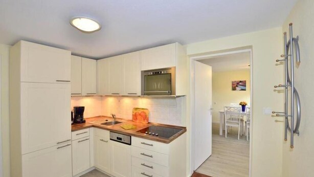 A compact kitchen with white cabinets, a built-in oven, and a coffee maker.