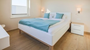 Ein Schlafzimmer mit Bett, Nachttischen, einem Fenster und einem Beistelltisch.