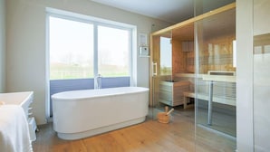 Ein modernes Badezimmer mit freistehender Badewanne, einer Duschkabine aus Glas und einem Holzbadezimmermöbel.