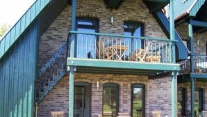 A two-story building with a balcony, wooden chairs, and a table. - Zur Alten Schmiede II Wohnung Oben I (Boltenhagen)