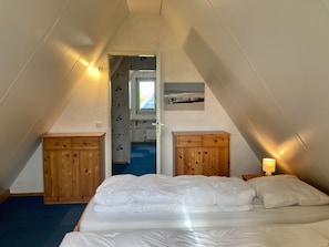 A bedroom with a bed, wooden cabinets, a lamp, and a painting on the wall.