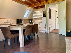 A compact kitchen with a dining area, wooden beams on the ceiling, and a view through an open door. - Holiday Home de Druif 6p With a Nice Terrace Near Lake Lauwersmeer (Anjum)