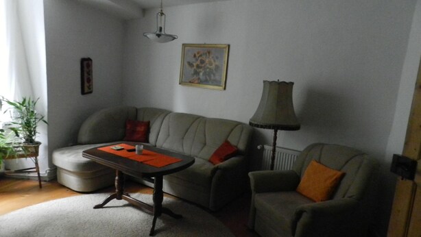 A living room with a sofa, a table, a lamp, and a radiator.