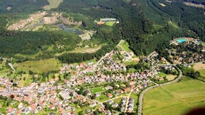An aerial view of a residential area with houses, roads, and a lake. - Ferienhaus Pahl in Wolfshagen (Langelsheim)