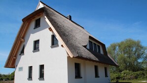 A traditional house with a steeply pitched roof, multiple windows, and a stone foundation. - Fewo Hiddenseeblick (Dranske)