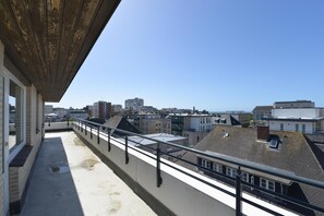 Un balcón con vistas a un paisaje urbano, con varios edificios y cielo despejado.