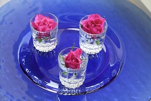 Tres jarrones de vidrio con flores rosadas sobre una bandeja de vidrio azul.