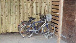 Una bicicleta assegurada a una estructura de fixació en una zona coberta, amb una tanca de fusta al fons.